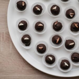 Top-down view of assorted chocolate pralines elegantly arranged on a white plate.